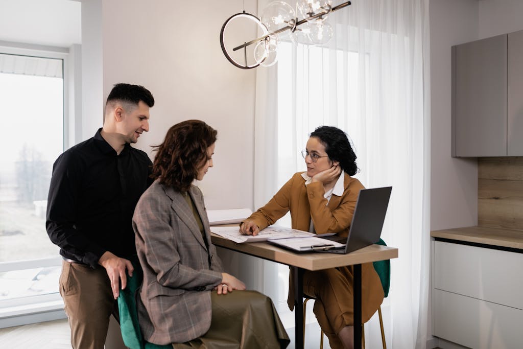 A couple consults a real estate agent in a modern office setting looking to get a last will and testament drafted.