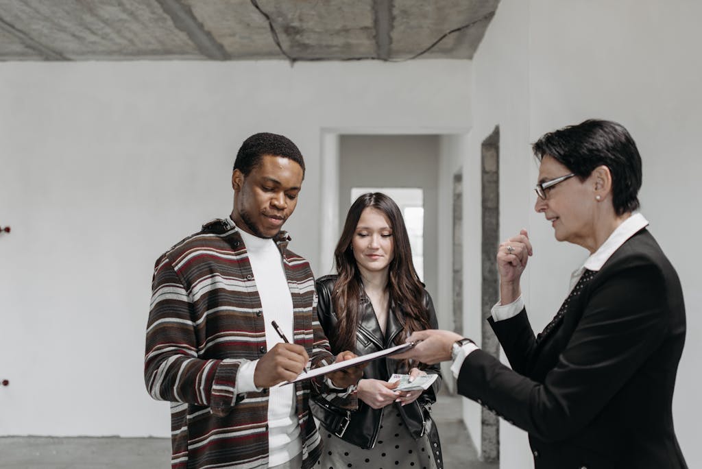 A diverse couple signing a quit claim deed with a realtor in a new home setting.