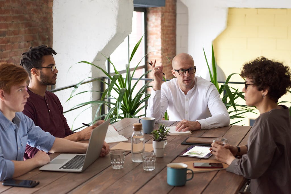 A group of colleagues in a modern office having a strategic discussion about a conflict of interest policy for non profits around a wooden table.