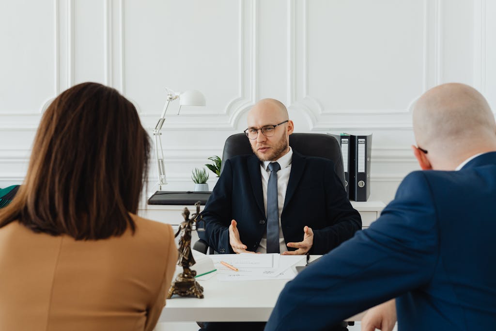 A professional business meeting with a lawyer and clients about a business contract review in a modern office setting.