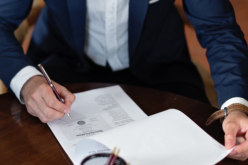 A professional individual signs legal documents at a desk in an office setting to enforce his clients trademark rights against infringement.