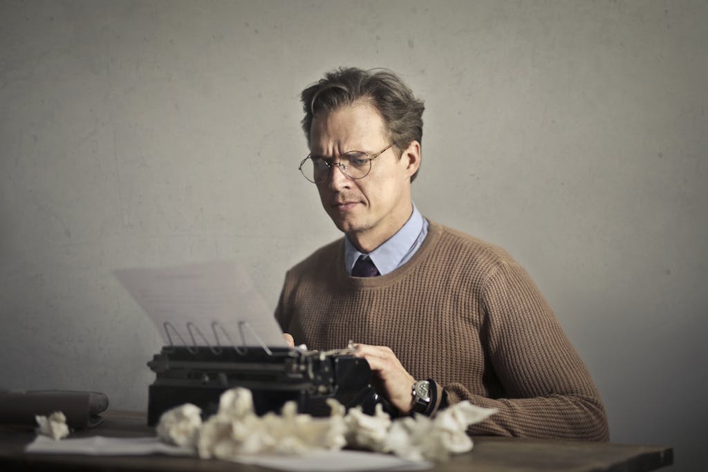A thoughtful writer using a typewriter surrounded by crumpled paper, embodying vintage creativity learning about the mistakes to avoid when writing a will.