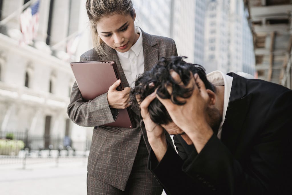 A woman comforts a distressed man in a business environment outdoors trying to work out how to protect your business from a lawsuit by going over some asset protection strategies. 