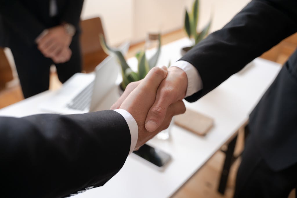 Close-up of a handshake between two professionals in a business setting, symbolizing agreement. But a breach of contract will later occur. 