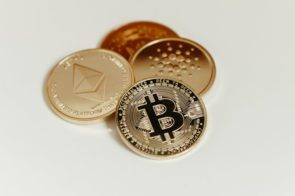 Close-up of Bitcoin, Ethereum, and Cardano coins on a plain background, showcasing digital assets.