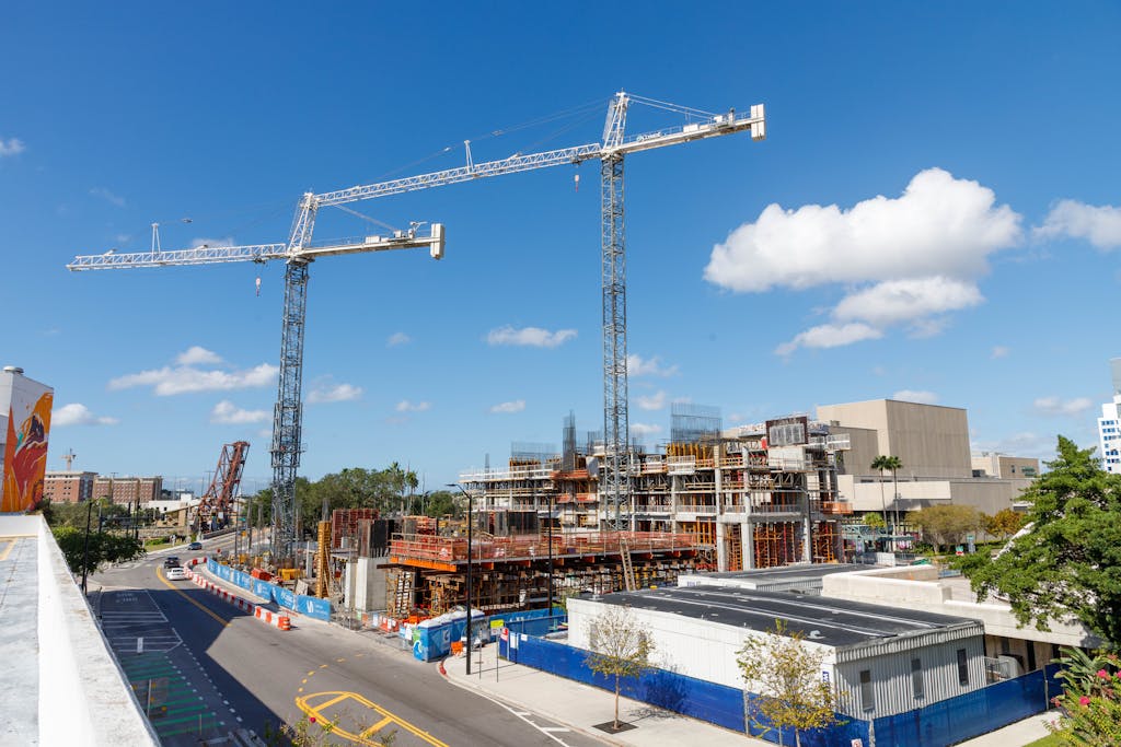 Construction cranes tower over a busy urban site in Tampa, Florida highlighting the need for Tampa construction law attorneys under a clear blue sky.