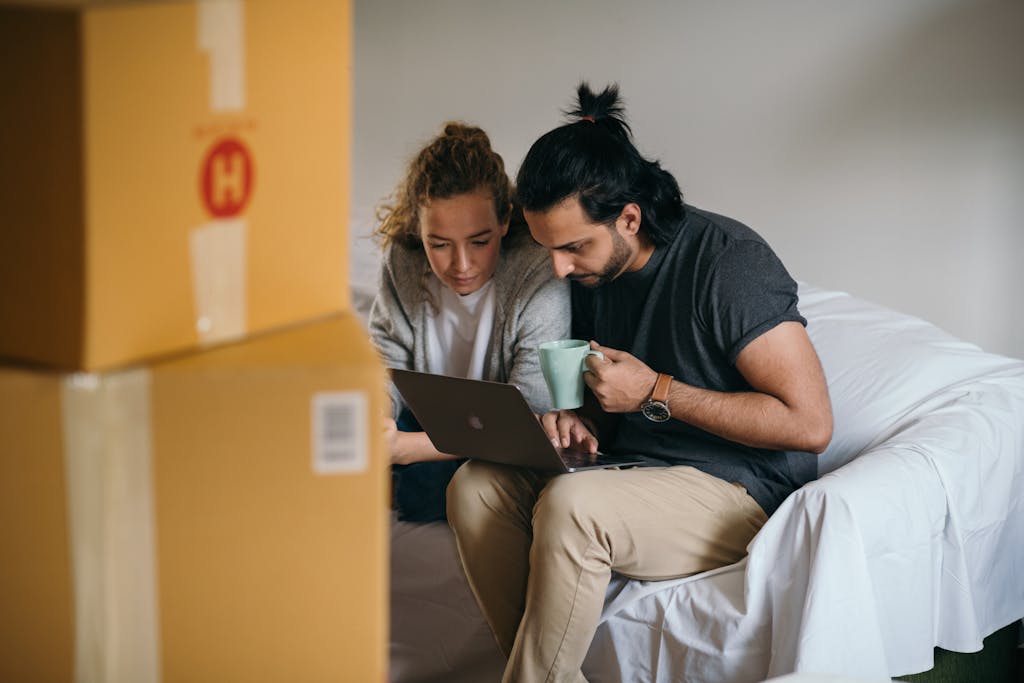 Couple surrounded by boxes checking laptop for real estate attorneys after facing a lis pendens.