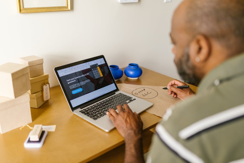 Entrepreneur at a desk using a laptop for business planning of an anonymous LLC. Ideal for tech and startup themes.