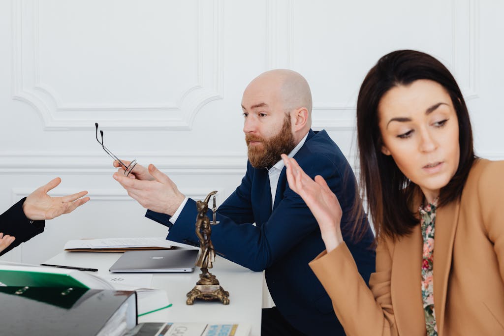 Three adults in a heated partnership dispute with legal documents, indoors.