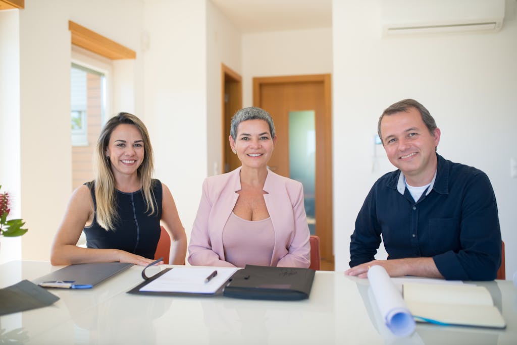 Three professionals smiling at a business meeting in a modern office who just formed a family office.